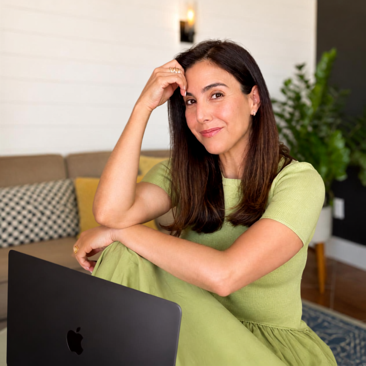 Camille in a green dress working on her laptop